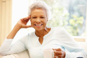 Old woman with white top sitting and smiling