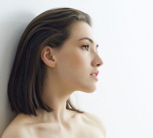 Woman with black hair leaning against wall